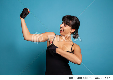 Portrait of athletic fit woman in sportwear showing am muscles Portrait of athletic fit woman in sportwear showing am muscles 86220357