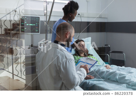Through the window view of nurse putting oxygen mask on unconscious female patient 86220378