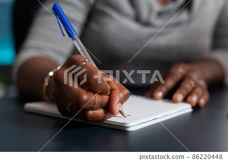 Close up of hand holding pen to write on textbook file Close up of hand holding pen to write on textbook file 86220448