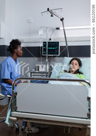 Nurse sitting down in hospital ward monitoring patient vitals on screen writing medical report 86220596