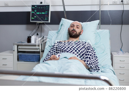 Patient lying in hospital bed with respiratory problems connected to monitor measuring vitals 86220800