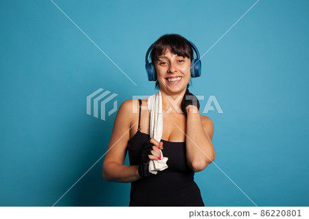 Smiling active trainer wearing headphones listening music Smiling active trainer wearing headphones listening music 86220801