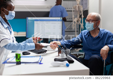 Physician doctor with face mask against covid19 stamping medication prescription 86220968