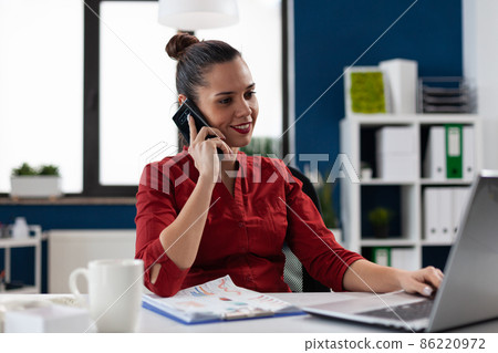 Smiling entrepreneur in red shirt talking on smartphone. Smiling entrepreneur in red shirt talking on smartphone. 86220972