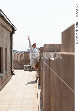 Caucasian female tourist rising hand while standing on tower rooftop Caucasian female tourist rising hand while standing on tower rooftop 86220974