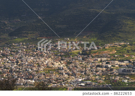 A view of a populated area village in a green valley in the morning at sunrise, against a dramatic back of mountains and clouds shadow. Travel concept hiking. North District Israel A view of a populated area village in a green valley in the morning at sunrise, against a dramatic back of mountains and clouds shadow. Travel concept hiking. North District Israel 86222653
