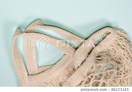Empty mesh bag on a blue background, top view. Space for text, eco-friendly shopping bag Empty mesh bag on a blue background, top view. Space for text, eco-friendly shopping bag 86223165
