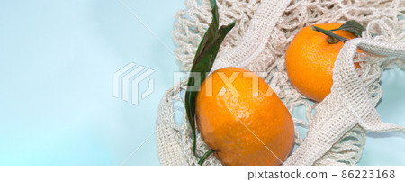 Blue banner background with tangerines in a string bag. Healthy lifestyle, top view, zero waste Blue banner background with tangerines in a string bag. Healthy lifestyle, top view, zero waste 86223168