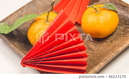 Chinese New Year, composition with tangerines, funny origami made of red paper on a dark wooden plate on a white background Chinese New Year, composition with tangerines, funny origami made of red paper on a dark wooden plate on a white background 86223170