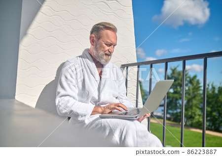Focused gentleman with the laptop sitting outdoors 86223887