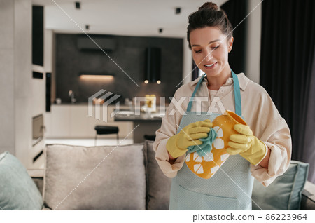 A woman in gloves cleaning an orange vase 86223964