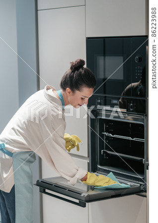 Service person cleaning the kitchen appliances Service person cleaning the kitchen appliances 86223988
