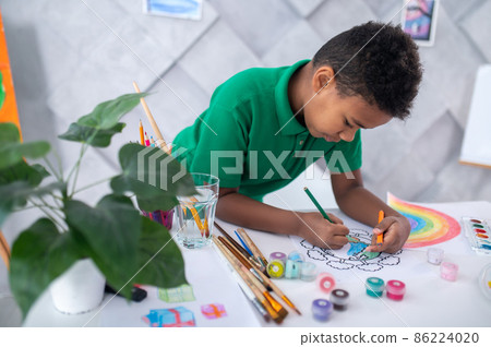 Boy drawing with color pencil standing at table 86224020