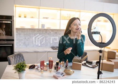 Young woman demonstrating new lip gloss and looking excited Young woman demonstrating new lip gloss and looking excited 86224243