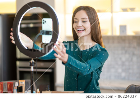 Pretty young woman fixing camera for conducting online workshop Pretty young woman fixing camera for conducting online workshop 86224337