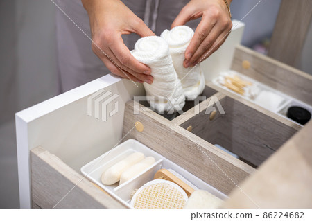 Top view of woman hands neatly organizing bathroom amenities and toiletries in drawer in bathroom. 86224682