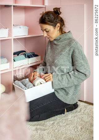 Happy young mother enjoying tidying up at female child wardrobe closet neatly folded clothes Happy young mother enjoying tidying up at female child wardrobe closet neatly folded clothes 86225672