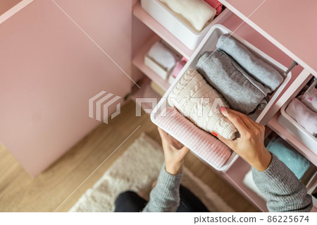 Happy young mother enjoying tidying up at female child wardrobe closet neatly folded clothes Happy young mother enjoying tidying up at female child wardrobe closet neatly folded clothes 86225674