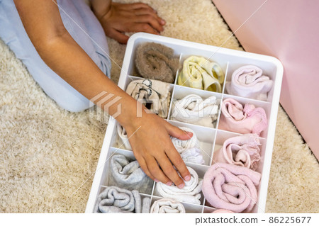 Happy girl neatly roll folded underwear and socks in plastic container box Marie Kondo method Happy girl neatly roll folded underwear and socks in plastic container box Marie Kondo method 86225677