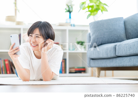一個女人面朝下躺在客廳裡操作智能手機 一個女人面朝下躺在客廳裡操作智能手機 86225740