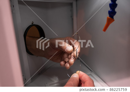 The technician solders the metal frame of the glasses. 86225759