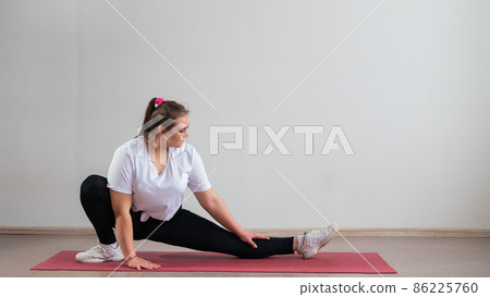 Young fat woman doing flexibility exercises on a white background 86225760