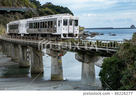 The white Nichinan Line limited express Umisachi Yamasachi runs under the waves that hit the blue sky and blue sea of southern Kyushu and the strange rocks created by the power of nature. The white Nichinan Line limited express Umisachi Yamasachi runs under the waves that hit the blue sky and blue sea of southern Kyushu and the strange rocks created by the power of nature. 86226277