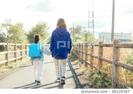 Parent and child walking toward the setting sun 86226367