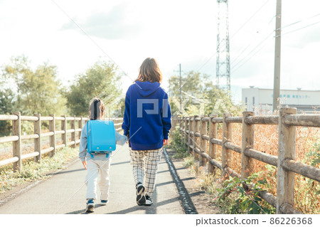 Parent and child walking toward the setting sun 86226368