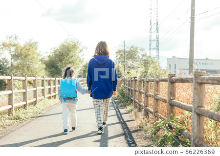 Parent and child walking toward the setting sun 86226369