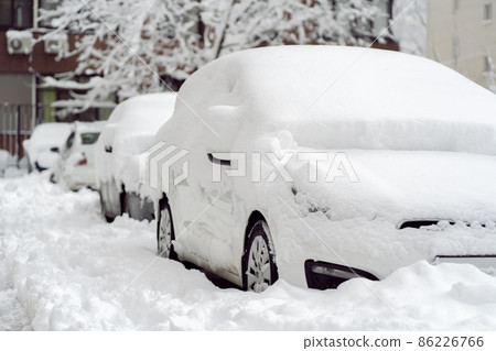 Snowfall in the city. Car covered in several inches of snow. Car almost totally buried Snowfall in the city. Car covered in several inches of snow. Car almost totally buried 86226766