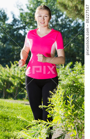 Sportswoman in pink T-shirt is jrunning around Sportswoman in pink T-shirt is jrunning around 86227587