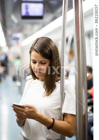 Woman using phone in subway car Woman using phone in subway car 86228037