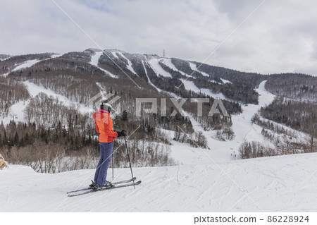 Skiing woman. Alpine ski - skier looking at mountain view against snow covered trees and ski in winter. Mont Tremblant, Quebec, Canada. 86228924