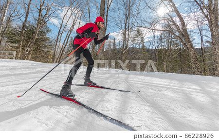 Cross Country Skate Skiing Style - Man on Nordic Ski in Forest in winter doing fun endurance winter sport activity in the snow on cross country ski in beautiful nature landscape 86228926