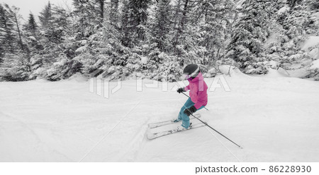 Skiing Downhill. Woman on ski going downhill having fun on the slopes on a snowy day - Winter sport and activities 86228930