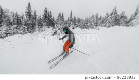 Skiing man. Alpine ski - skier going dowhill against snow covered trees background in winter nature landscape. Ski holidays vacation concept Skiing man. Alpine ski - skier going dowhill against snow covered trees background in winter nature landscape. Ski holidays vacation concept 86228932