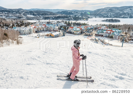 Skiing woman. Alpine ski - skier looking mountain village ski resort view starting skiing downhill on snow covered ski trail slope in winter. Mont Tremblant, Quebec, Canada 86228950