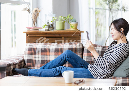 一位穿著日常服裝的女士看著平板電腦的屏幕 86230592