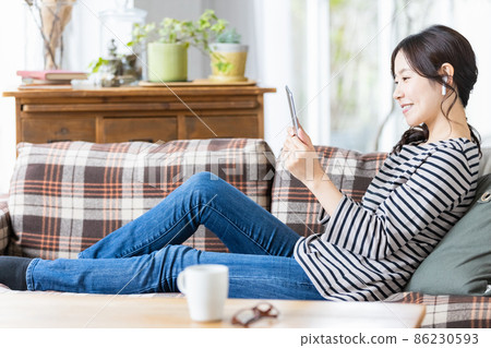 一位穿著日常服裝的女士看著平板電腦的屏幕 86230593