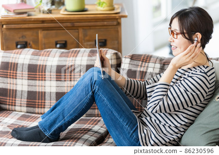 一位穿著日常服裝的女士看著平板電腦的屏幕 86230596