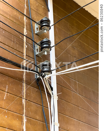 The spool Insulators in the electric wire system on the building wall. The spool Insulators in the electric wire system on the building wall. 86230840