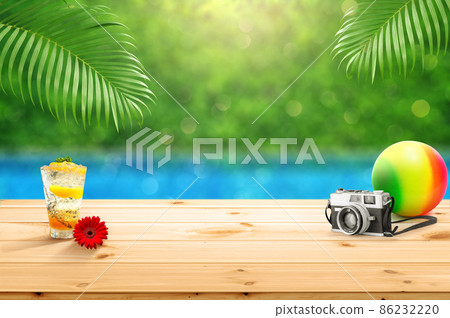Wooden table top with with accessories glass of fruit juice camera and beach ball isolate with blured swimming pool background with palm leaves as frame montage for product advertisement Wooden table top with with accessories glass of fruit juice camera and beach ball isolate with blured swimming pool background with palm leaves as frame montage for product advertisement 86232220