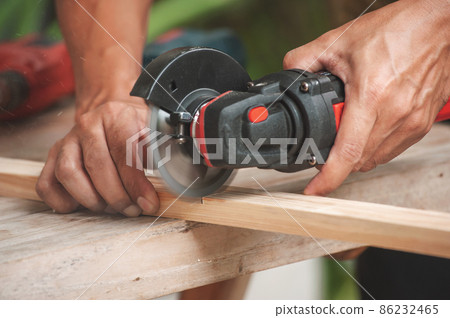 Close up of a carpenter using a circular saw to cut a wood 86232465