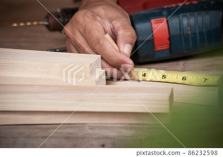 Hands of a carpenter taking measurement of a wooden plank ,Wood working concept Hands of a carpenter taking measurement of a wooden plank ,Wood working concept 86232598