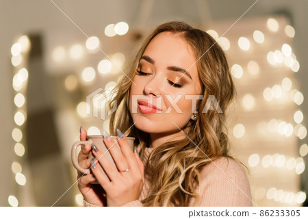 Beautiful young woman celebrating christmas at home, having fun while opening presents Beautiful young woman celebrating christmas at home, having fun while opening presents 86233305