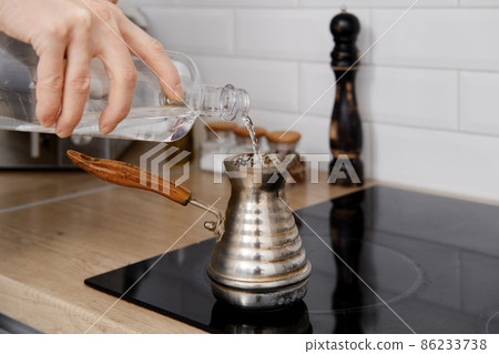 Closeup view of man pouring water into cezve with ground coffee 86233738