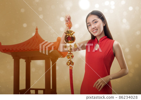 Asian Chinese woman in a cheongsam dress holding Chinese ornament 86234028