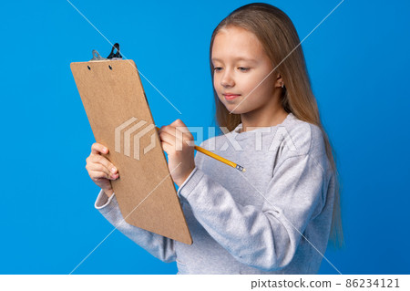 Portrait of little cute girl making notes against blue background 86234121