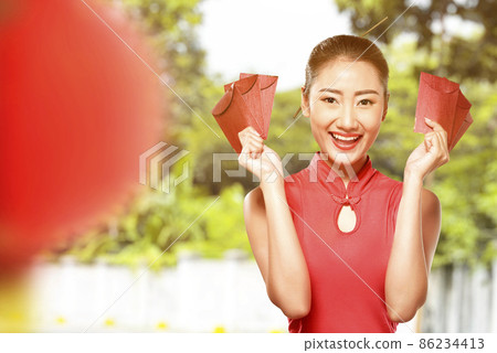 Asian Chinese woman in a cheongsam dress holding red envelopes Asian Chinese woman in a cheongsam dress holding red envelopes 86234413